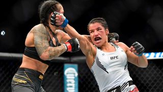 Julianna Pena punches Amanda Nunes of Brazil in their women's bantamweight championship bout during UFC 269 