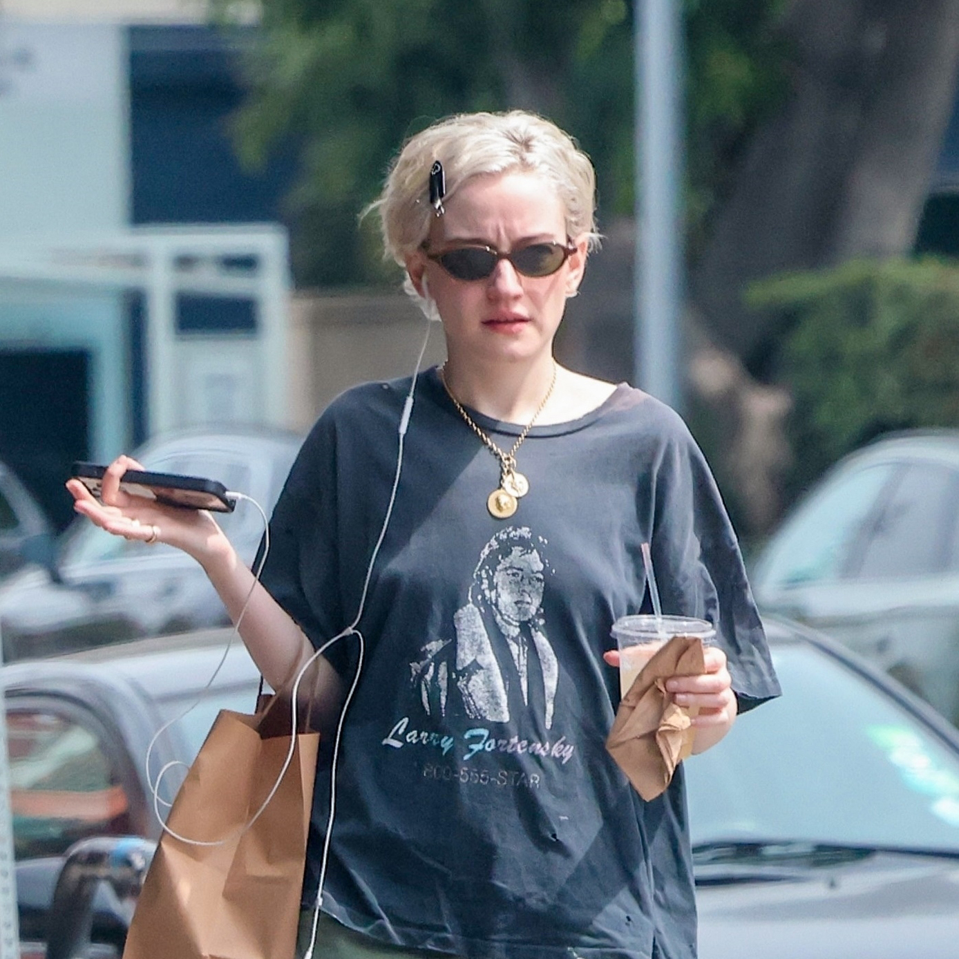 Julia Garner wearing a navy graphic tee, green barrel pants, and Puma ballet flats