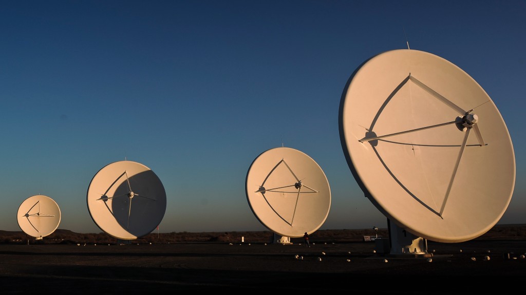 Quatre grands radiotélescopes sont assis sur une plaine plate.