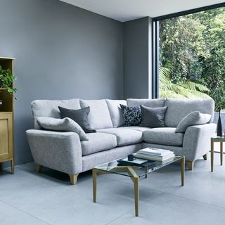 living room with grey wall grey sofa with designed cushions and glass door