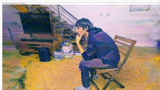 Pointillism effect applied to scene of man sitting on a chair in cluttered living room