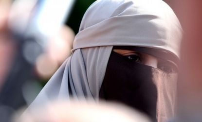 A young woman wearing a niqab is surrounded by media Monday in Paris: The country's ban on veils and headscarves sparked protests throughout France.