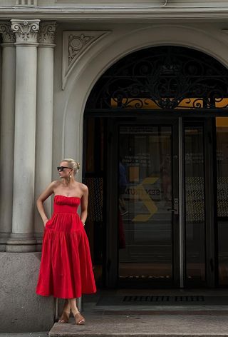 a photo of a woman wearing a strapless red dress and tan mules