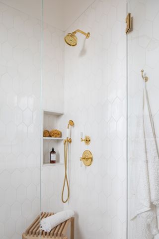 shower area with white tiling and gold hardware