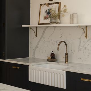 Navy kitchen with white butlers sink and marble backsplash