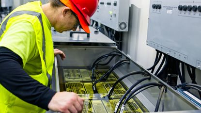 A data center technician overseeing a rack submerged in an immersion cooling tank.