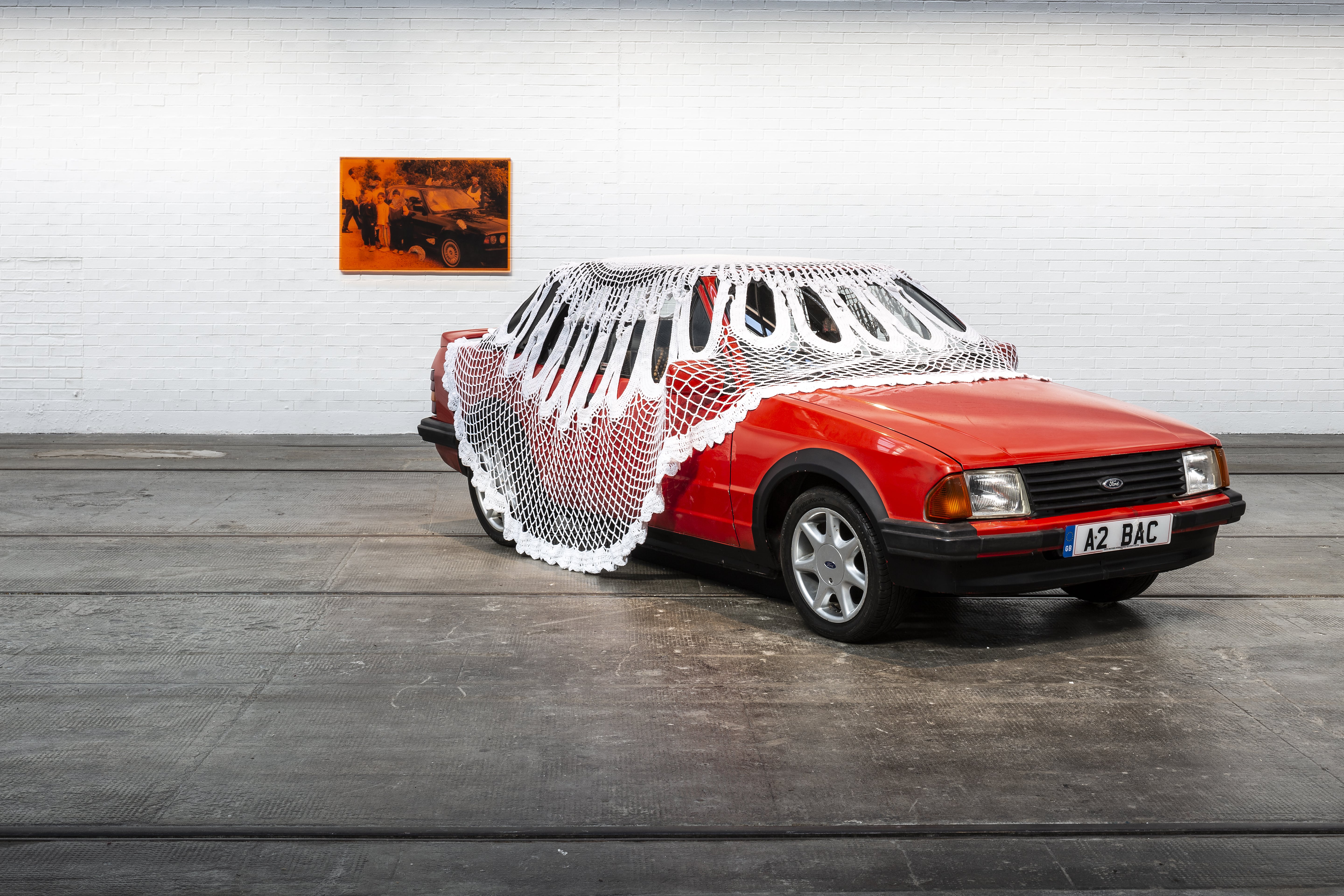 car with doily covering, artwork in gallery