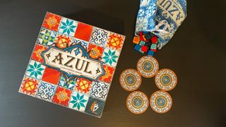 Azul board game box, tokens, and bag on a black wooden table