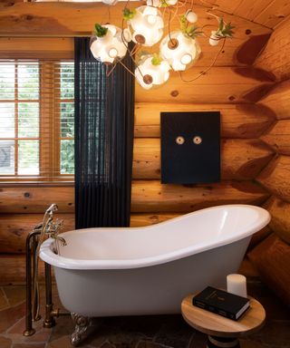 bathroom with wooden walls and roll top bath and modern chandelier