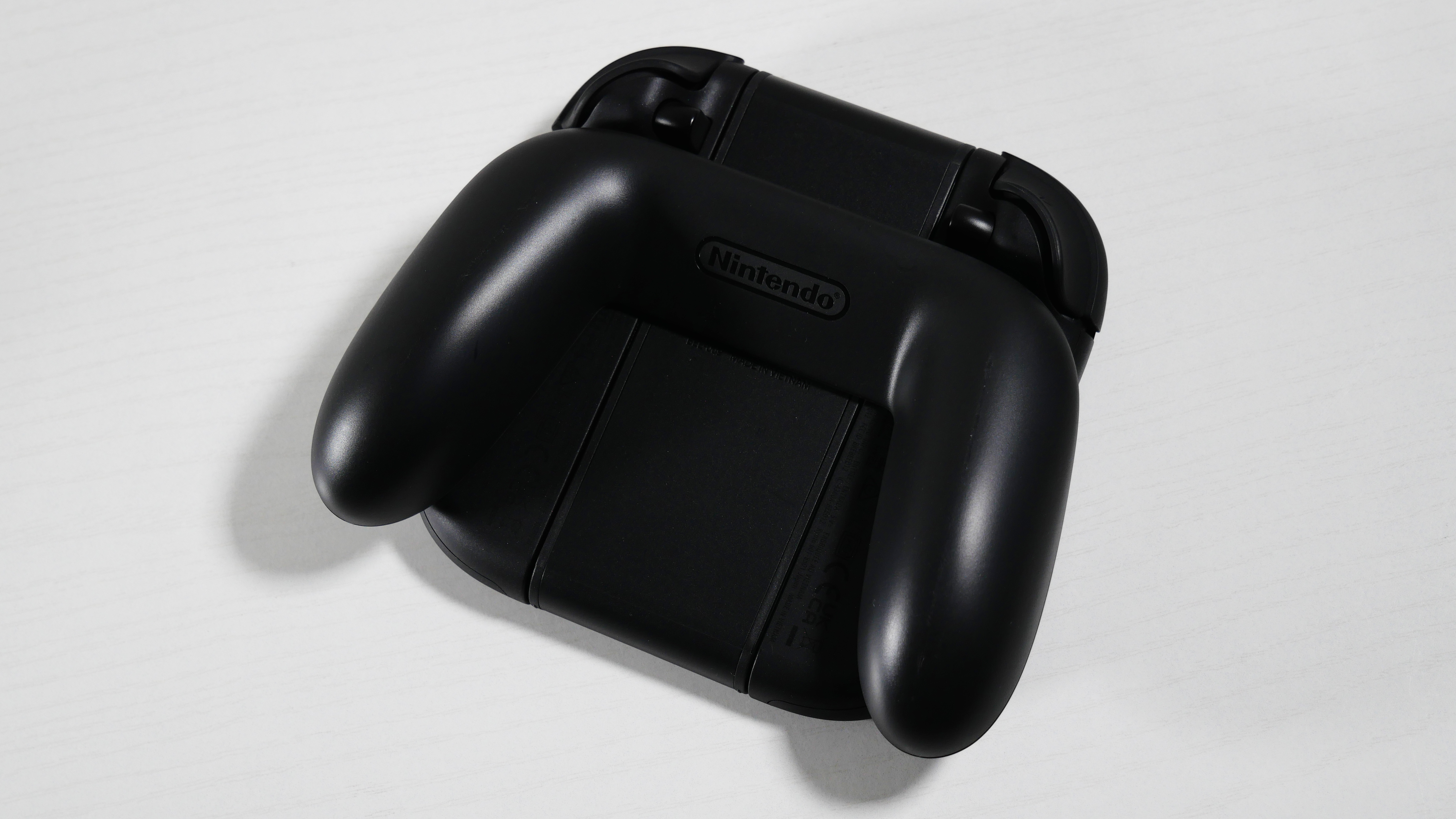 Nintendo Switch 2 Joy-Con 2 Grip lying on its front on a white desk.