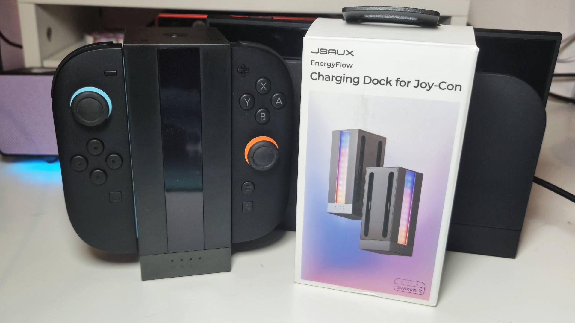 Photo of the Jsaux Energy Flow with two Switch 2 Joy-Con attached, with its box sitting to its side.