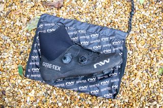 A black Northwave Flagship GTX shoe and shoe bag on some gravel