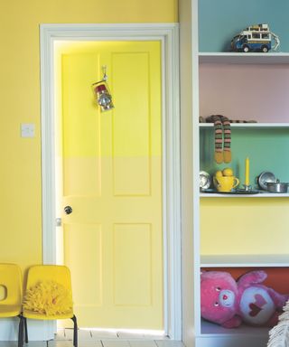 yellow playroom with different colored shelves, yellow childrens chairs, toys, ombre yellow painted door