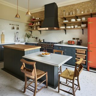 split-level island kitchen with wooden chairs and orange fridge