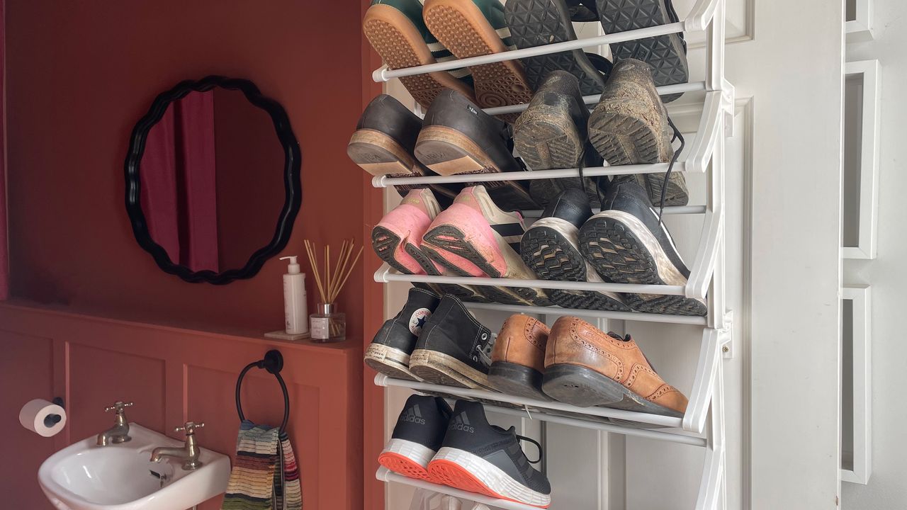 White shoe rack on the back of a white door with terracotta bathroom behind