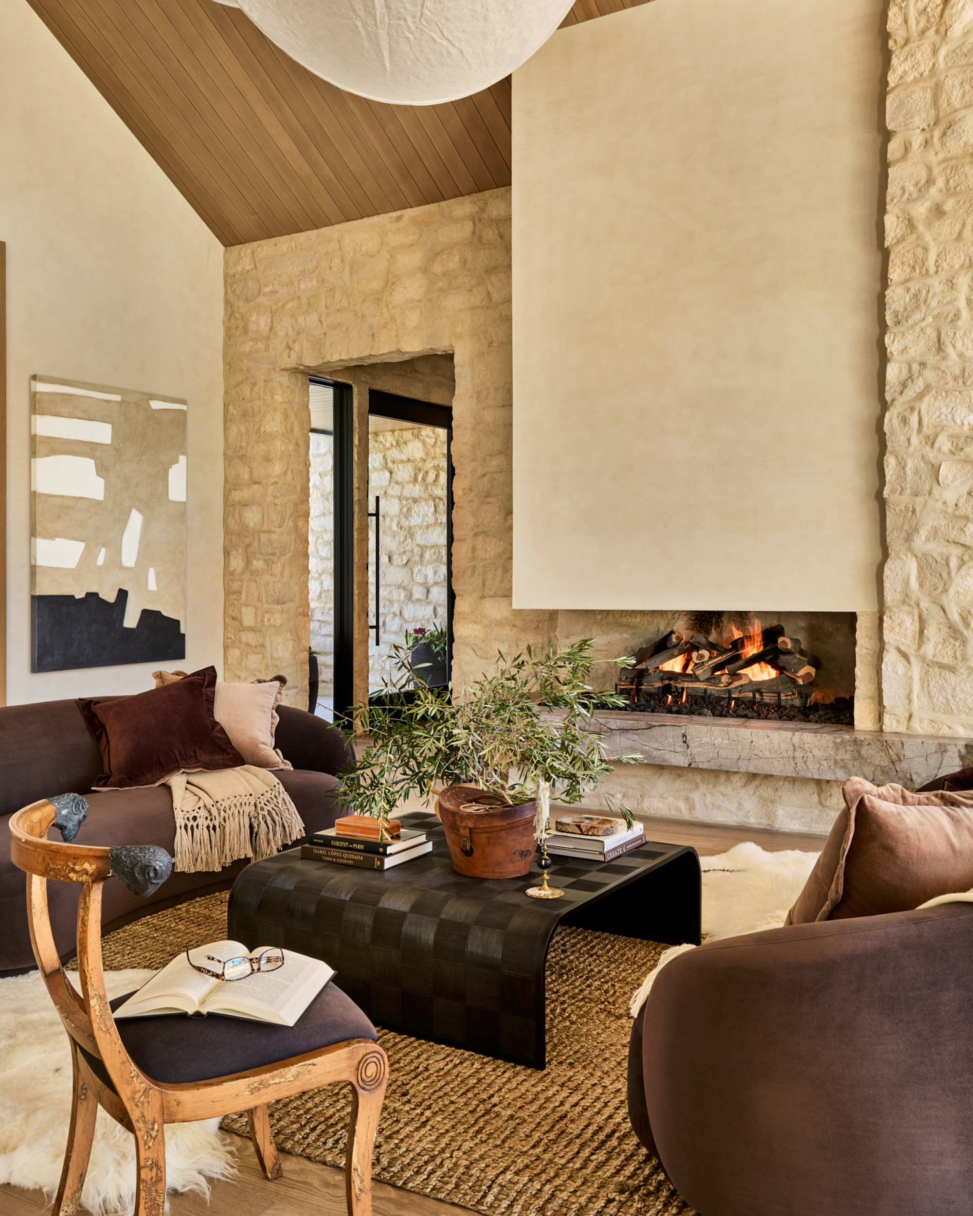 A living room with a neutral color palette, brick walls, a fireplace, and two brown curved sofas