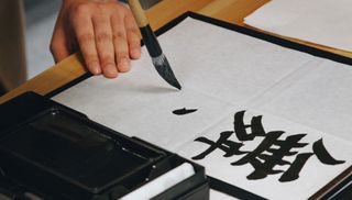 person doing calligraphy on page