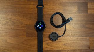 OnePlus Watch med laddsladden på ett bord.