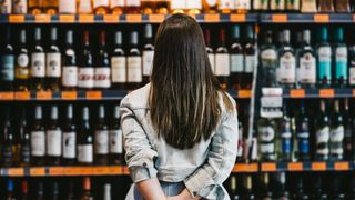Woman looking at wall of wine bottles in a supermarket
