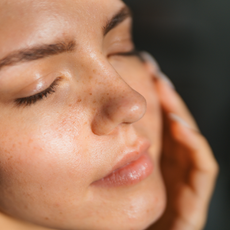 A woman closes her eyes and touches her face as she bathes in the sun's light