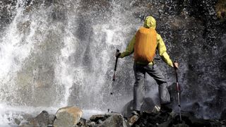 Hiker walking near a waterfall wearing a dry bag