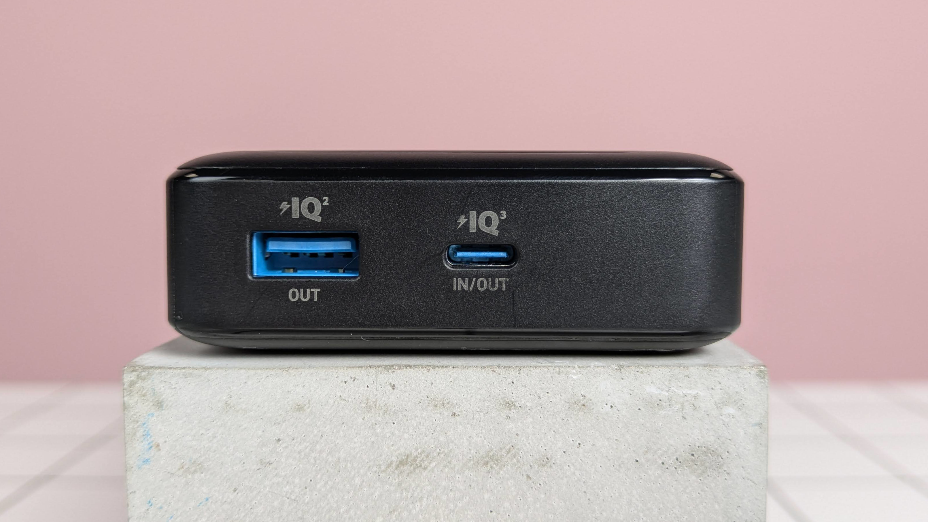 Close-up of ports on Anker 20,000mAh 87W Power Bank, on plinth on desk, with pink background