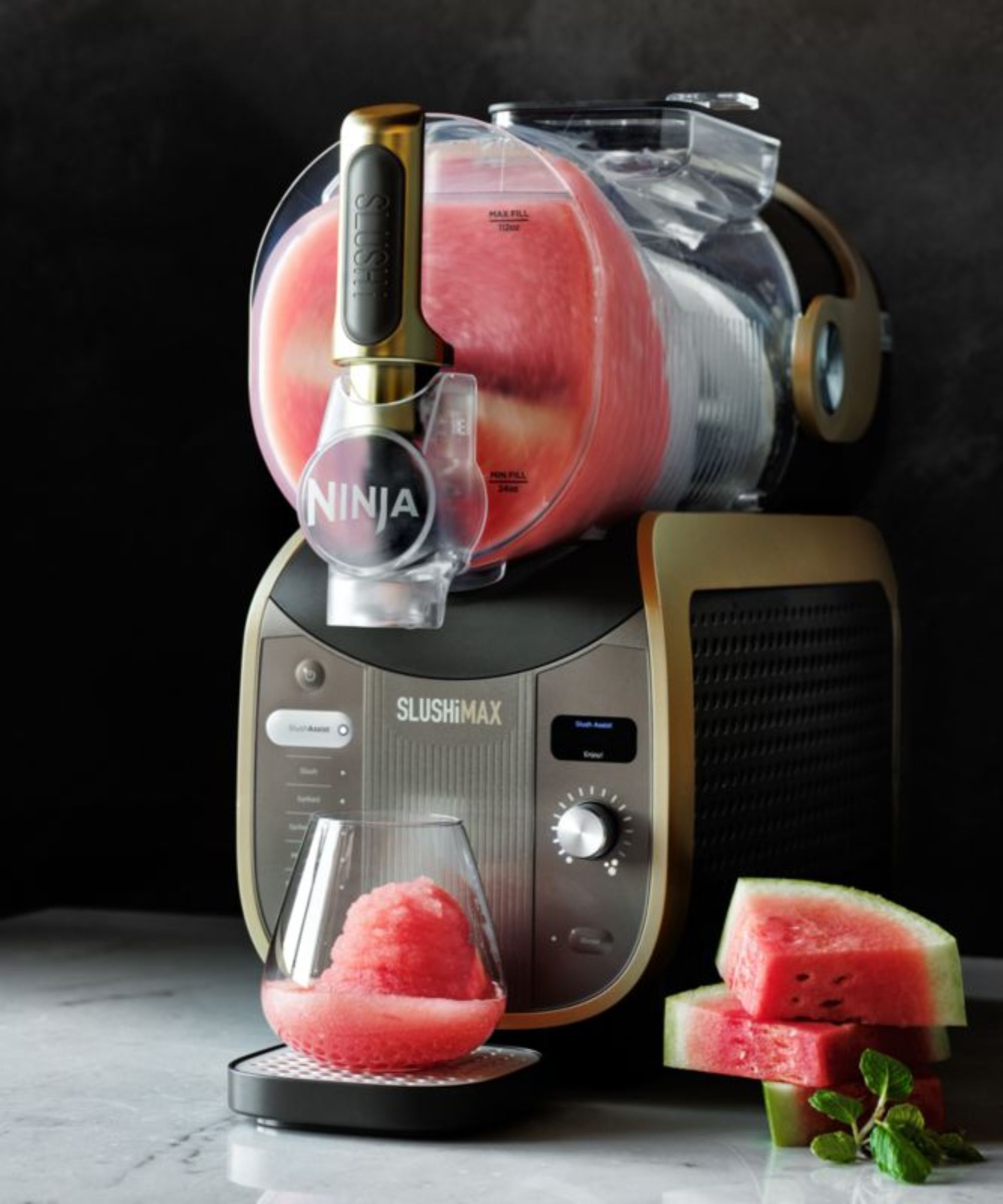 The black and gold Ninja Slushi Max machine filled with pink slush mix, dispensed into a glass below.