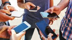 A group of young people using their smartphones, only their hands and phones showing.