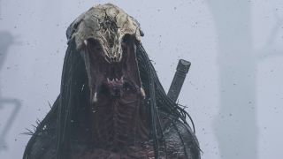 Close up image of the alien Predator&#039;s face. It has long dreadlocks, sharp mandibles. and is wearing a skull as a helmet.