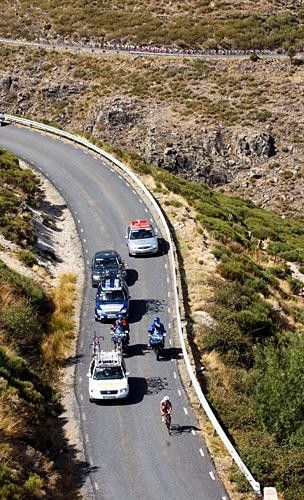 A breakaway rider is pursued by the peloton on a climb