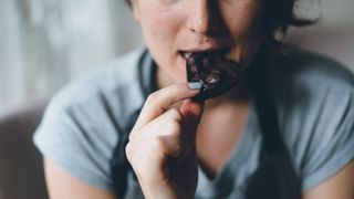 three foods you should never eat before bed - woman eating dark chocolate