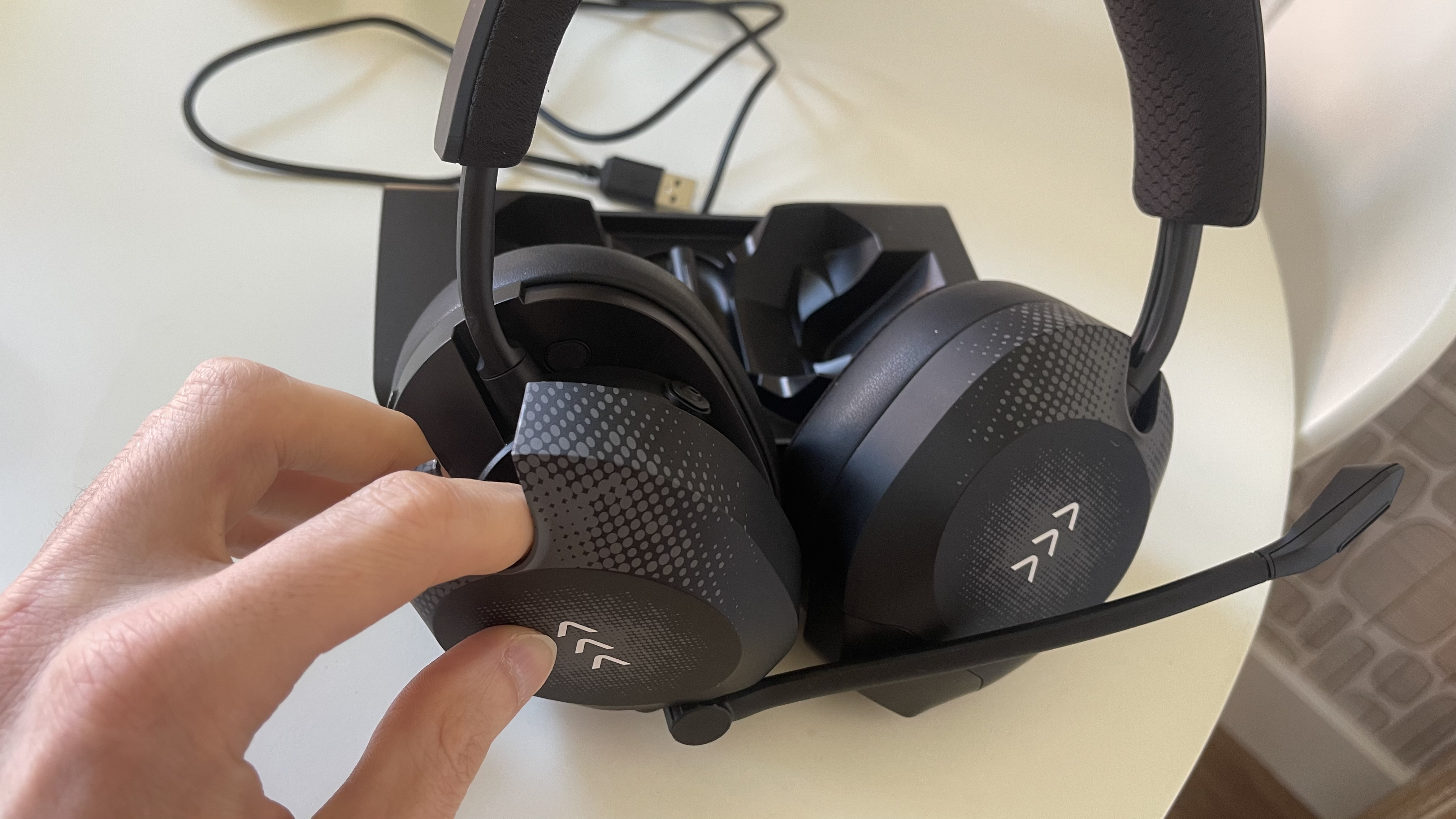 The RIG R8 PRO HS gaming headset on its base station sitting on a light coloured table