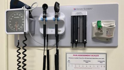 A variety of medical instruments are seen in the interior of a doctor's office, including a blood pressure cuff and pain scale.