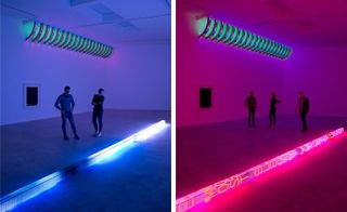 A man and a woman are standing next to the neon art installation in a dark-lit room. The installation is in a shape of a long beam with electronic neon writing on it. The photo on the left has a blue cast, and the photo to the right has a pink cast.