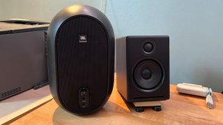 JBL and Audioengine computer speakers on wood desktop surface