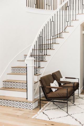 Staircase with alternating white and monochrome patterned risers, oak treads and black spindles