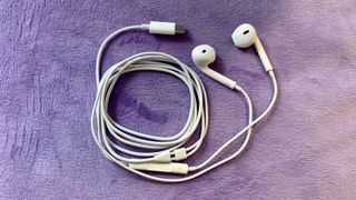 Apple USB-C EarPods on a purple cushion