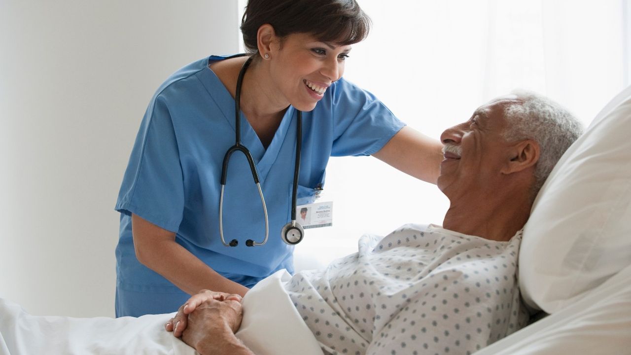 Man in hospital bed being cared for by nurse