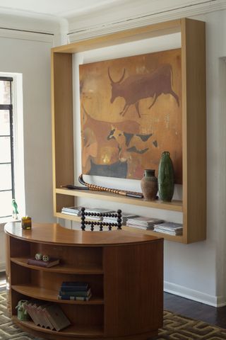 a curved desk in front of a floating wall unit with artwork inside