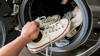 White converse sneakers being put into the washing machine.