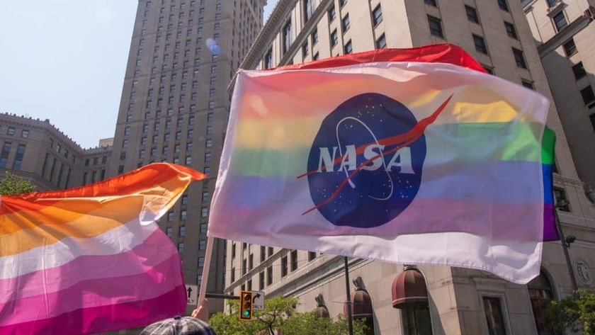 a white nasa flag waves in front of a rainbow pride flag