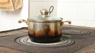 An old pan on a stove with burn marks around the base