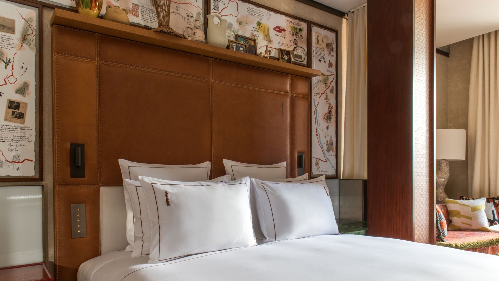 A hotel bed with a tall headboard and a painted map on the wall