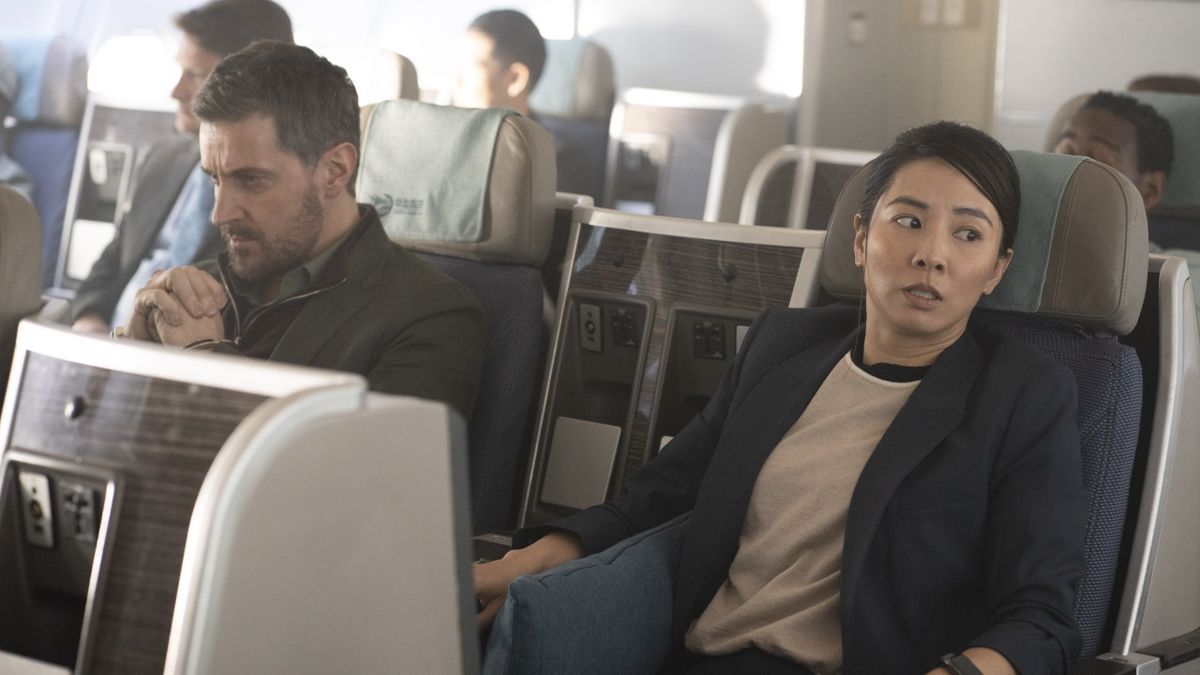 Dr Matthew Nolan (Richard Armitage), in handcuffs, sits alongside a panicked looking DC Hana Li (Jing Luci) aboard an passenger plane in Red Eye