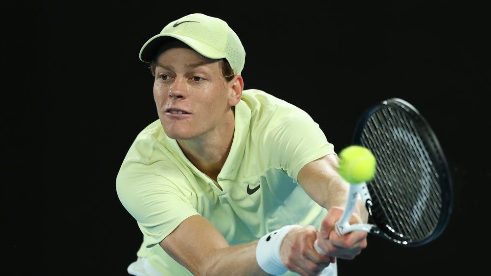 Jannik Sinner of Italy (yellow hat and shirt) plays a backhand against Alex de Minaur of Australia on his way to the Men&#039;s Singles final – Sinner vs Zverev – at the 2025 Australian Open at Melbourne Park in Melbourne, Australia.