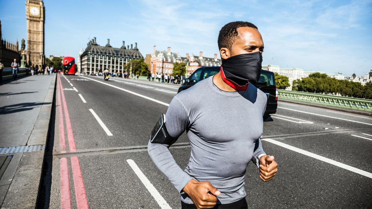 A man wearing a gaiter to cover his mouth and nose runs in central London.