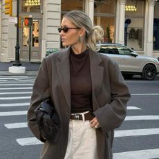 Influencer wears a brown belt with a wool coat and a dark brown fine knit jumper.