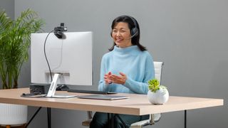 The new Logitech AI-powered headset being used by a woman at a desk on a computer video call. 