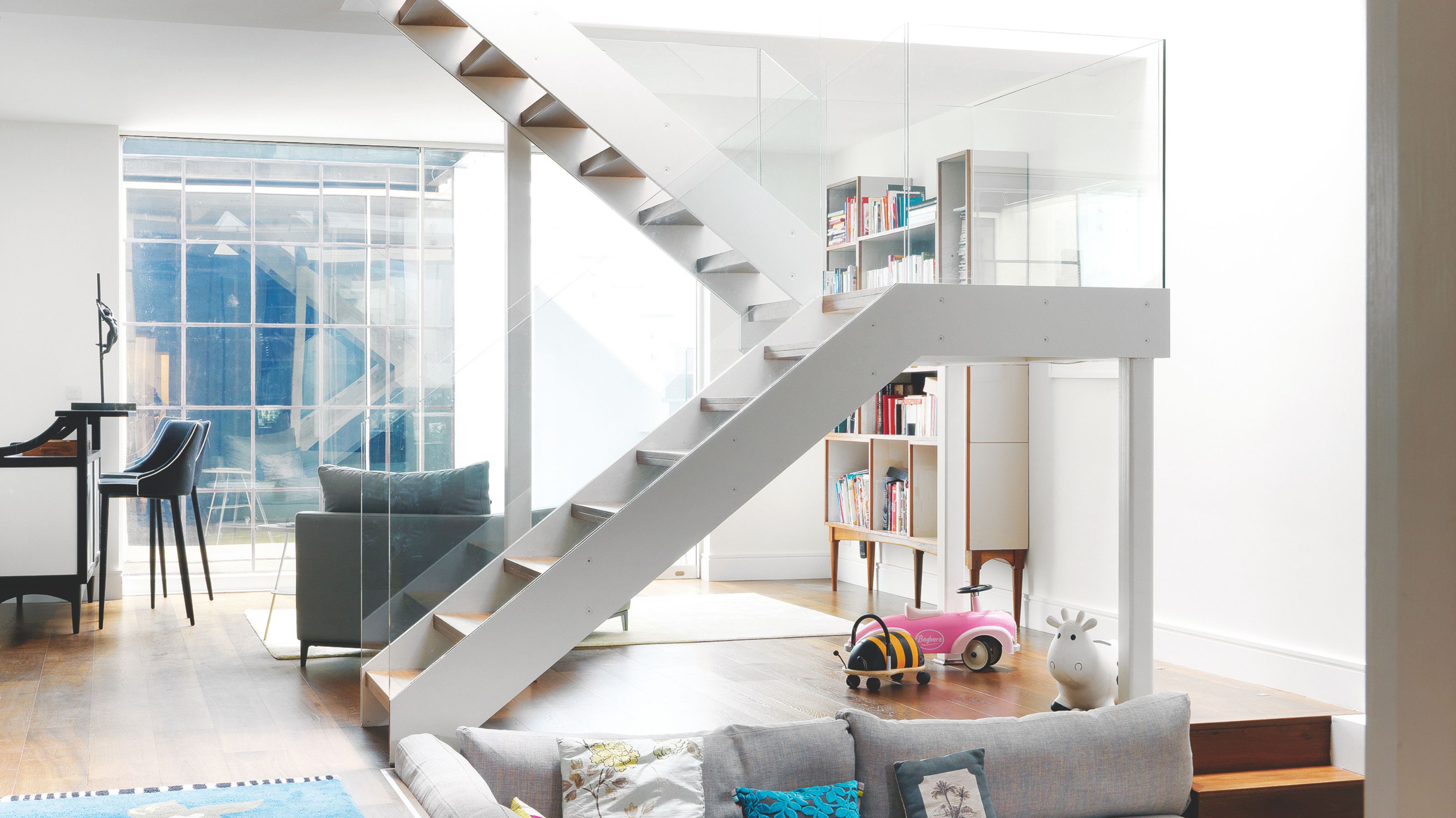 Half turn stairs leading to basement living space, with sunken living room and large window letting in lots of natural light