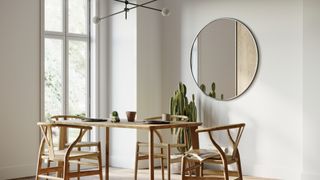 a modern dining room with a Scandi-style wooden dining table, and a mirror on the wall in the background